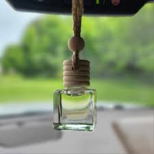 Car air freshener hanging from a rearview mirror with a scenic background